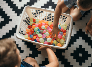 Kids filling up laundry basket with water balloons