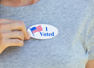 Woman in gray shirt wearing an I Voted Sticker
