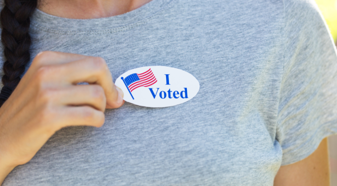 Woman in gray shirt wearing an I Voted Sticker