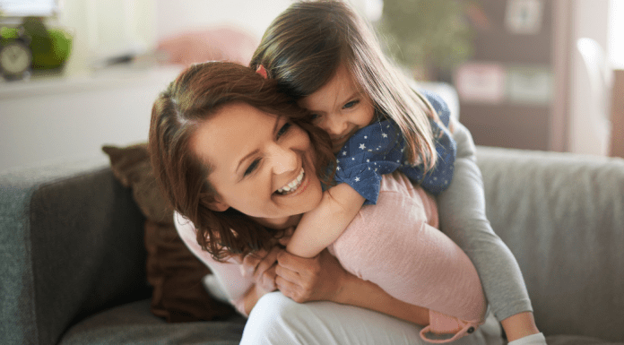 mom with young daughter hugging on a couch