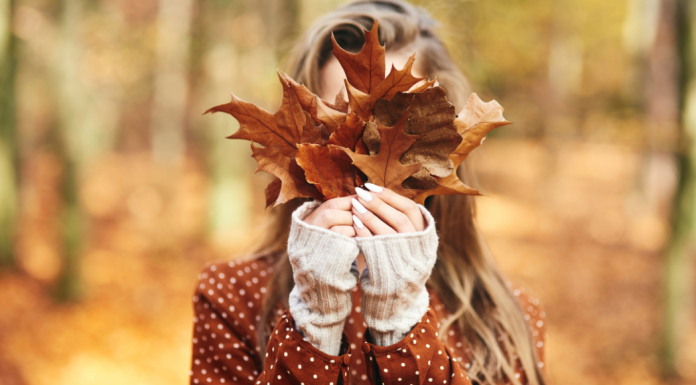 Woman outside holding fall leaves up to her face