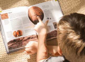 overhead shot of boy reading a book about planets