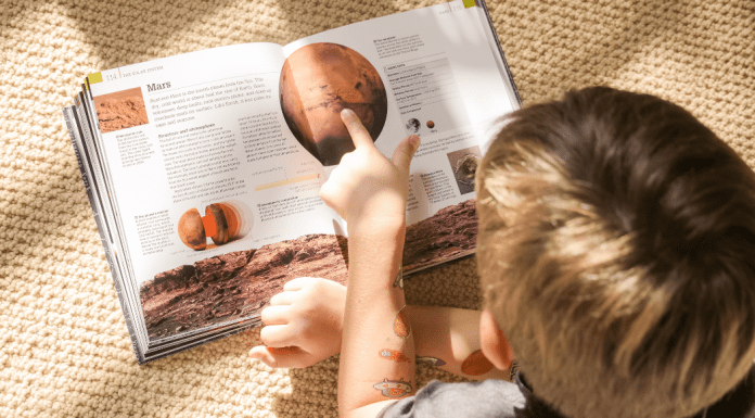 overhead shot of boy reading a book about planets