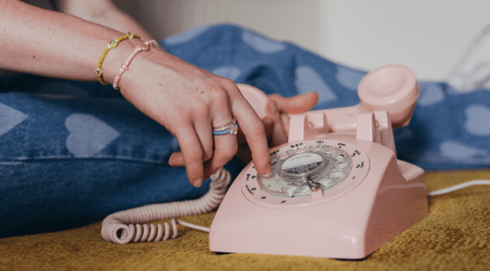Teenager using a pink rotary phone