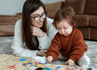 au pair sitting on a floor with a toddler doing puzzles