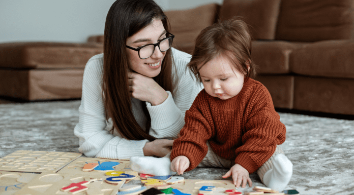 au pair sitting on a floor with a toddler doing puzzles