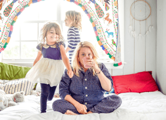 juggling motherhood featured image with a mom sitting on a bed with her kids
