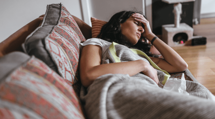 woman laying on couch while sick