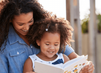 mom and daughter reading a book together outside