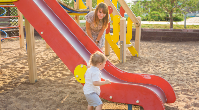 mom and child playing by a playground slide