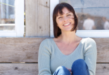 woman sitting against a wall outside smiling