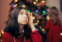 woman near christmas tree, stressed and holding her had to her head.