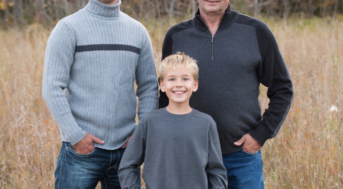 boy posing with two men in a field