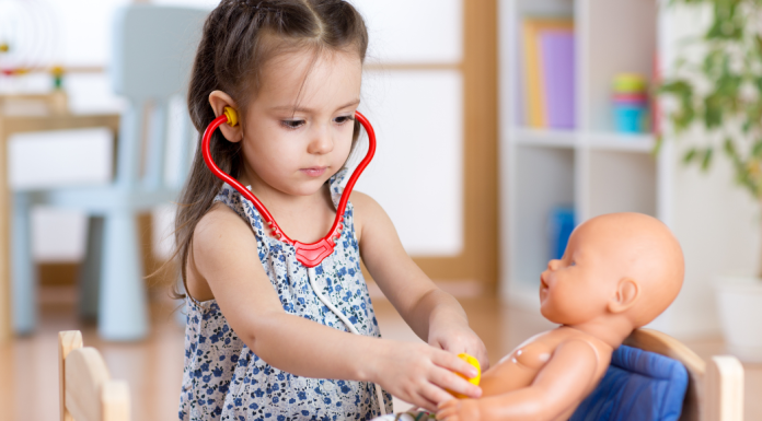 Child wearing a stethoscope as she plays with her doll.