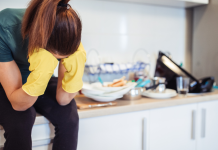 survival mode featured image with a woman wearing kitchen gloves sitting on a counter next to a pile of dirty dishes.